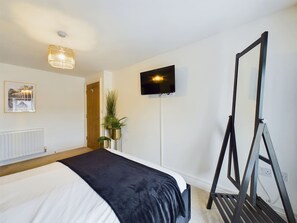 A hotel room with a bed, a television, a mirror, and a radiator. - Modern 4 Bed Walk to Pubs Shops and Countryside (Bishop Auckland)