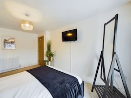 Una habitación de hotel con cama, televisión, espejo y radiador.