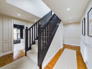 A staircase with black railings leading to a landing, a white wall with a framed picture, and a wooden floor. - Modern 4 Bed Walk to Pubs Shops and Countryside (Bishop Auckland)