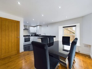 A modern kitchen with white cabinets, a black countertop, and a dining area with a black table and chairs. - Modern 4 Bed Walk to Pubs Shops and Countryside (Bishop Auckland)