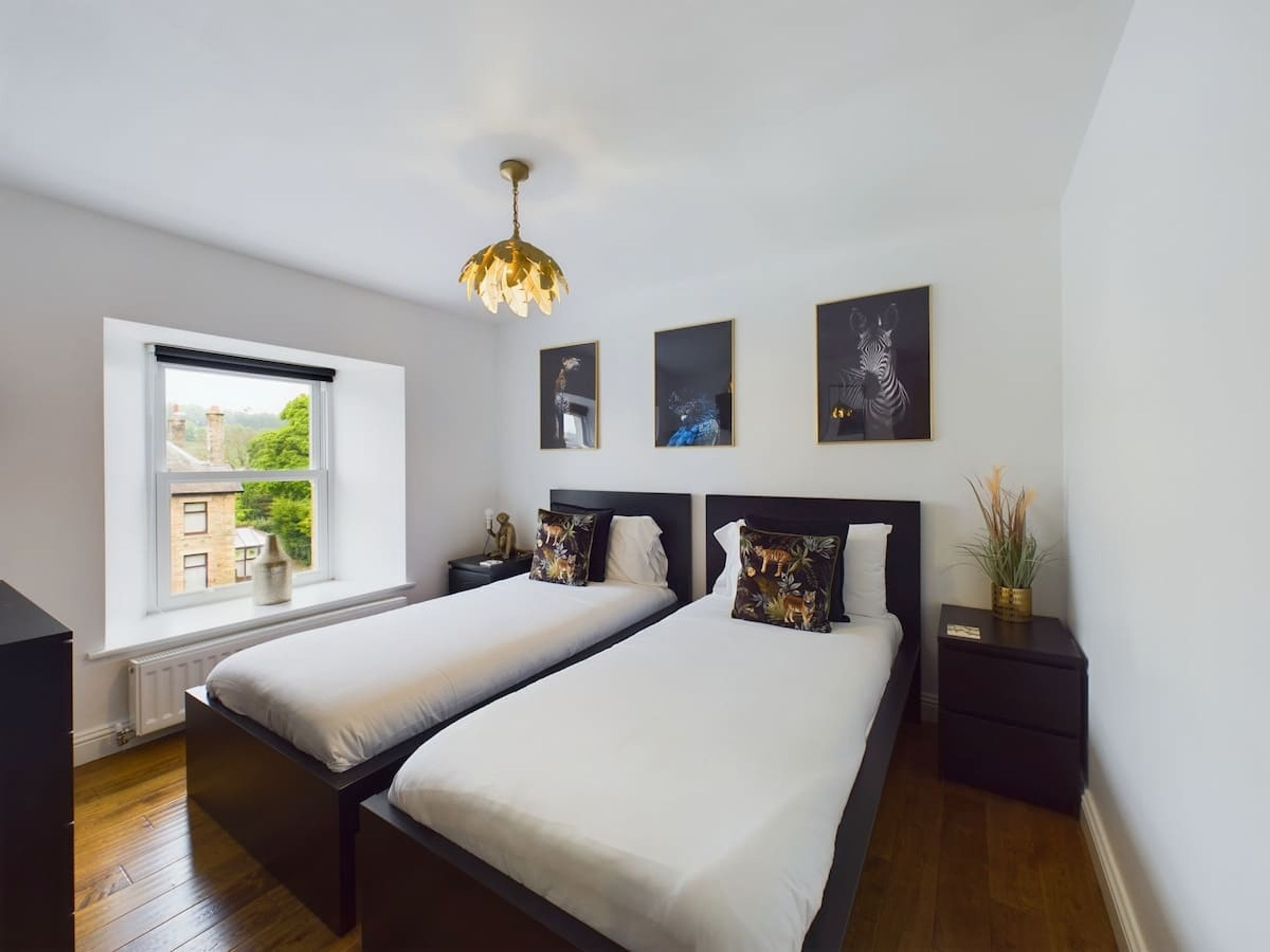 Un dormitorio con dos camas, una ventana con vistas y tres cuadros en la pared.