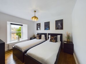A bedroom with two beds, a window with a view, and three framed pictures on the wall. - Modern 4 Bed Walk to Pubs Shops and Countryside (Bishop Auckland)