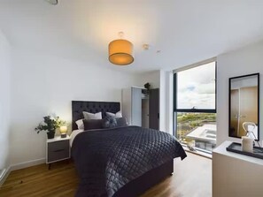 Ein modernes Schlafzimmer mit einem großen Bett, einem Nachttisch, einem Kleiderschrank und einem großen Fenster mit Blick.