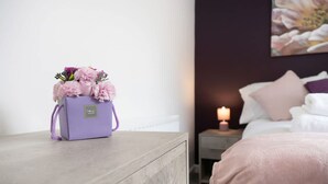 A room with a bed, a nightstand with a candle, and a purple bag with flowers on a wooden nightstand. - 3 Bed in Sunderland With Free Wifi (Sunderland)