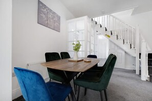 A dining area with a wooden table, green chairs, a blue chair, and a plant on the table. - 3 Bed in Sunderland With Free Wifi (Sunderland)
