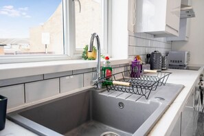 A kitchen with a stainless steel sink, a window, and a metal drying rack. - 3 Bed in Sunderland With Free Wifi (Sunderland)