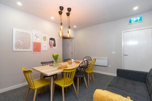 Een eethoek met een houten tafel en stoelen, een vaas met bloemen en wanddecoratie.