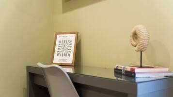 A desk with a framed artwork, a model shell, and a stack of books.
