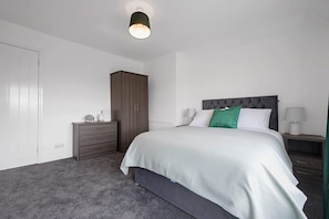 A bedroom with a bed, bedside tables, a wardrobe, and a ceiling light. - Stylish Home Near Durham Heritage Coast Sleeps 5 (Durham)