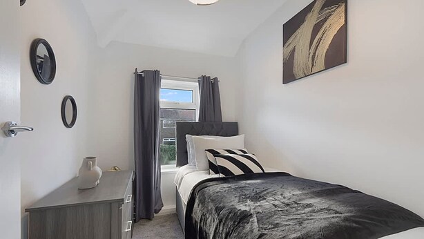 Een slaapkamer met een bed, een dressoir, een raam met gordijnen en een schilderij aan de muur.