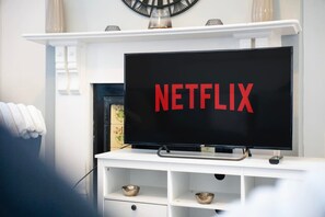 A television on a white stand with the Netflix logo displayed on the screen. - Family Friendly 2BR Close to Durham City (Durham)