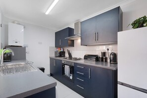 A modern kitchen with grey cabinets, a built-in oven, and a stainless steel range hood. - Family Friendly 2BR Close to Durham City (Durham)