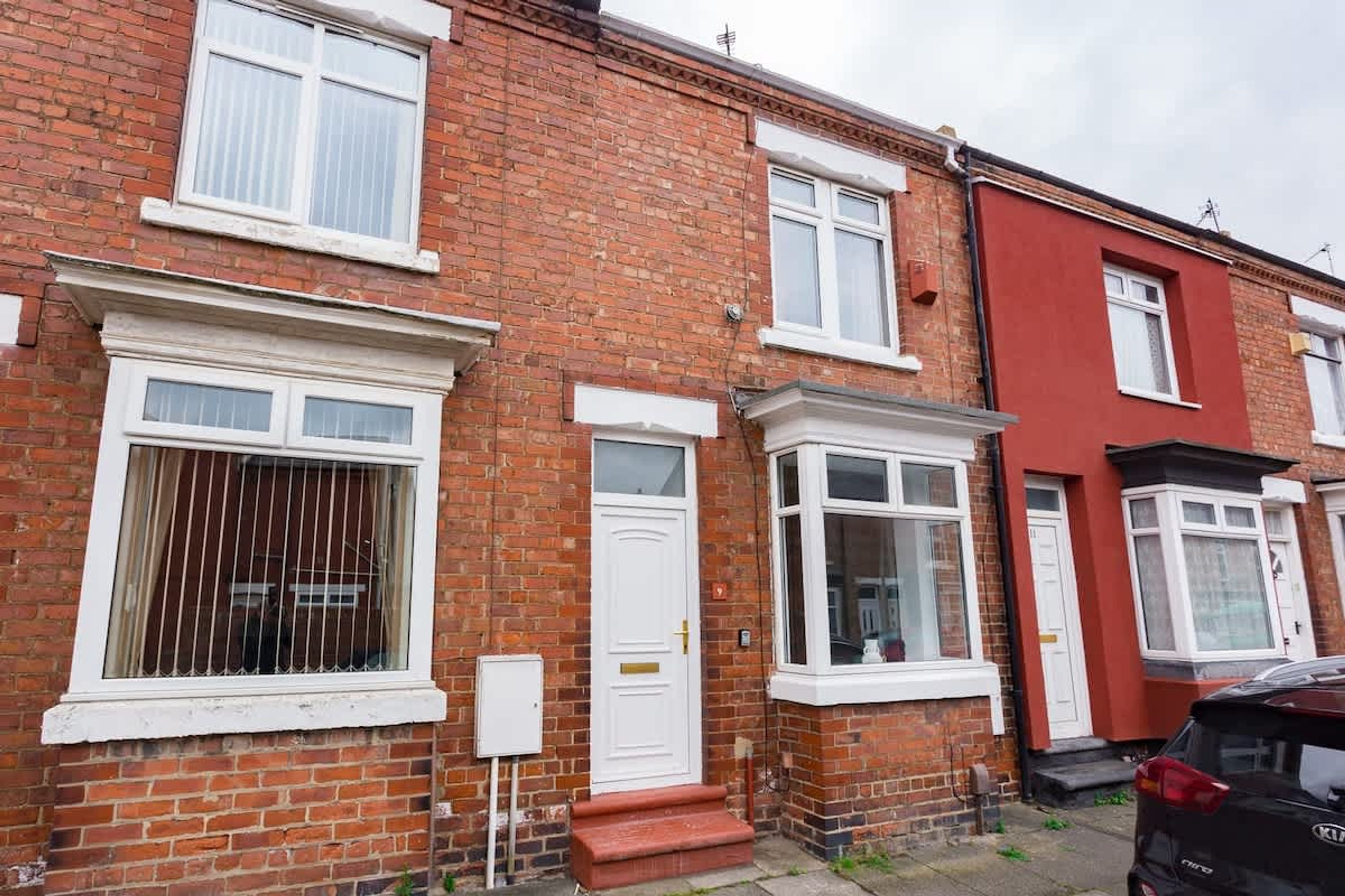 A row of terraced houses with brick facades, white-framed windows, and a red door.