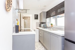 A modern kitchen with grey cabinets, a white countertop, and a window providing natural light. - Two Bedroom Family Apartment Near Town Centre Chic Stay (Darlington)