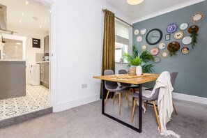 A dining area with a table, chairs, and a clock on the wall. - Two Bedroom Family Apartment Near Town Centre Chic Stay (Darlington)