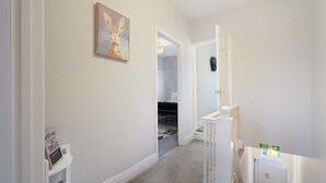 A hallway with a carpeted floor, a door leading to another room, and a small table with a sign. - Chic 2 Bed With Wifi Parking Ideal for Work Stay (South Shields)