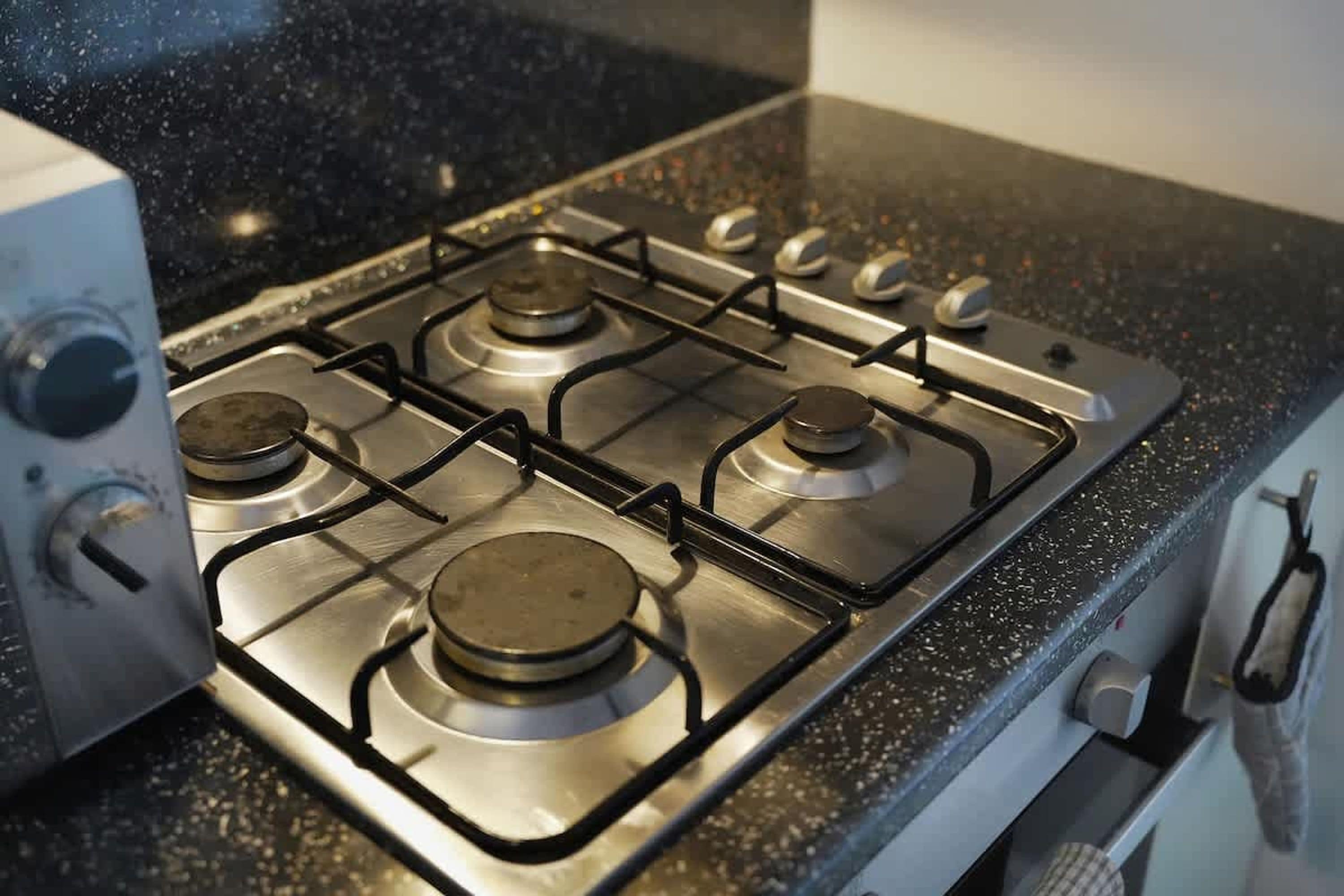 A kitchen with a gas stove, a range hood, and a stainless steel countertop.