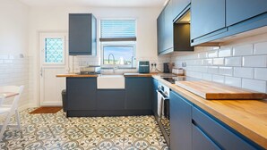 Uma cozinha moderna com ilha central, painel de azulejos brancos e uma janela com persianas.