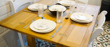 A dining table set with plates, glasses, cutlery, and a bowl.