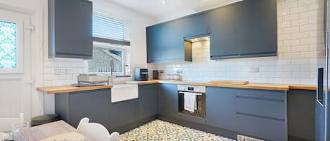 Une cuisine moderne avec des meubles gris, un four encastré et un sol à motifs.