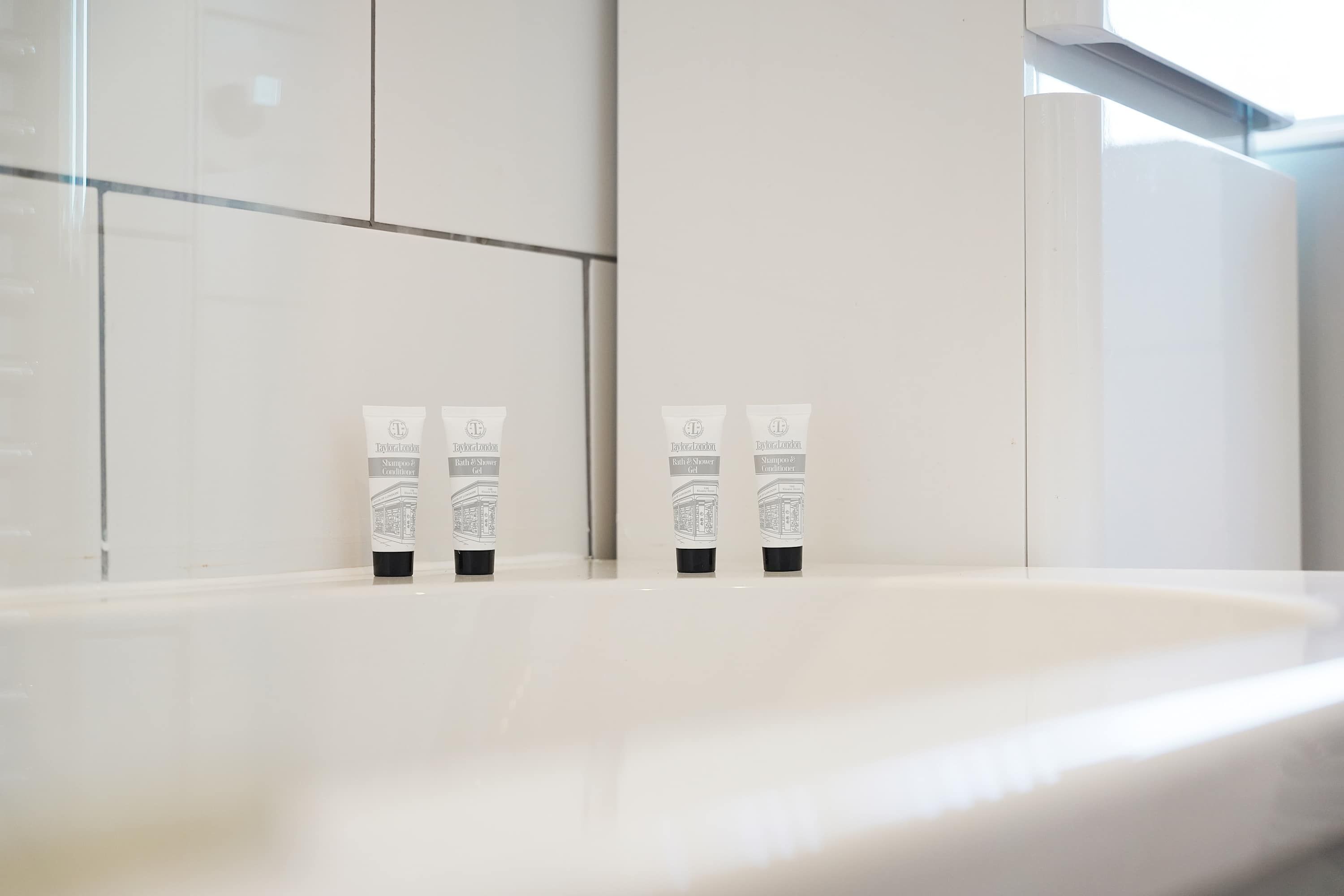 A bathroom with a white sink and three toiletry bottles on the counter.