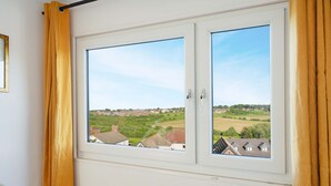 Janela com vista para uma área residencial, cortinas e moldura de porta.