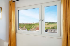 A window with a view of a residential area, curtains, and a door frame. - Chic 3BR Rotherham Parking Wifi By Stay With us (Rotherham)