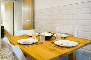 A dining table set with plates, cutlery, and glasses, with a white tiled wall in the background. - Chic 3BR Rotherham Parking Wifi By Stay With us (Rotherham)