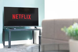 Un televisor sobre un soporte con la palabra 'NETFLIX' en la pantalla.