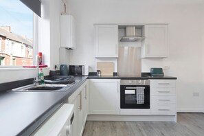 A modern kitchen with white cabinetry, a built-in oven, and a window providing a view of the outside. - Charming 3BR in Blyth (Blyth)
