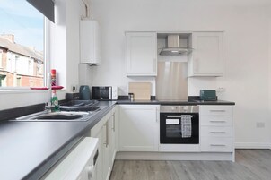 Cocina moderna con armarios blancos, horno empotrado y ventana con vistas al exterior.