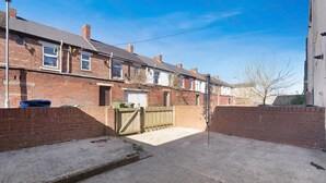 A residential street with terraced houses, a gated driveway, and a clear sky. - Charming 3BR in Blyth (Blyth)