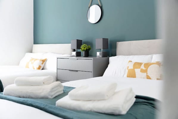 A hotel room with a bed, bedside tables, a mirror, and a wall-mounted light fixture. - Charming 3BR in Blyth (Blyth)
