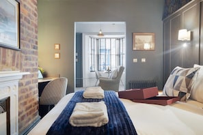 A hotel room with a bed, a desk, a chair, a fireplace, and a view of the city through the window. - Boutique Apartment in Hartlepool With Free Wifi (Hartlepool)