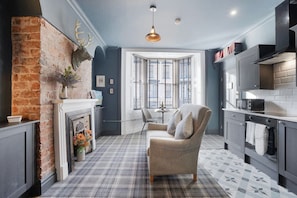A modern kitchen with grey cabinetry, a built-in oven, and a window with blinds. - Boutique Apartment in Hartlepool With Free Wifi (Hartlepool)