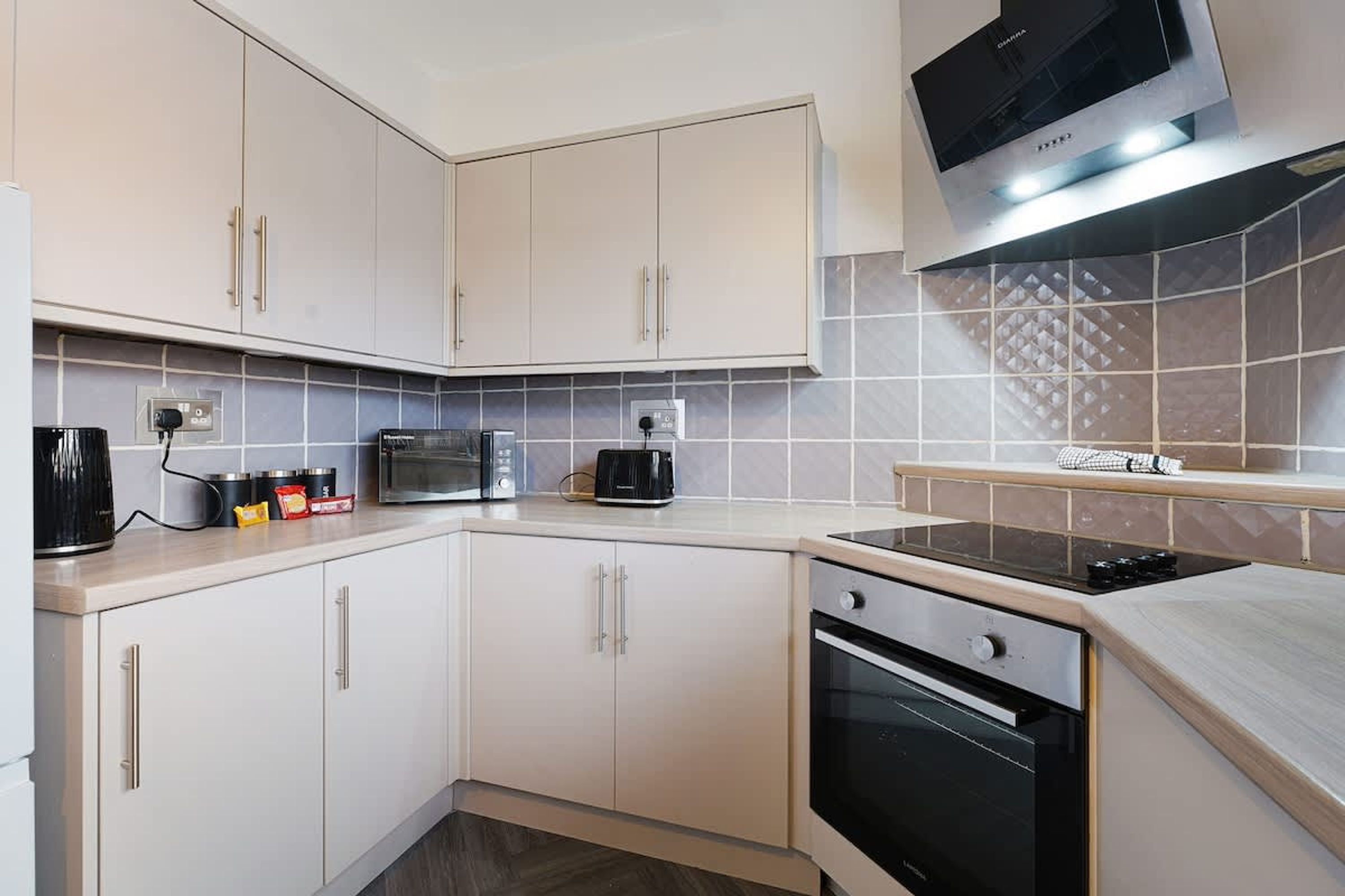 A modern kitchen with white cabinets, a microwave, a toaster, and a stove.