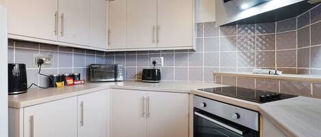 A modern kitchen with white cabinets, a microwave, a toaster, and a stove.