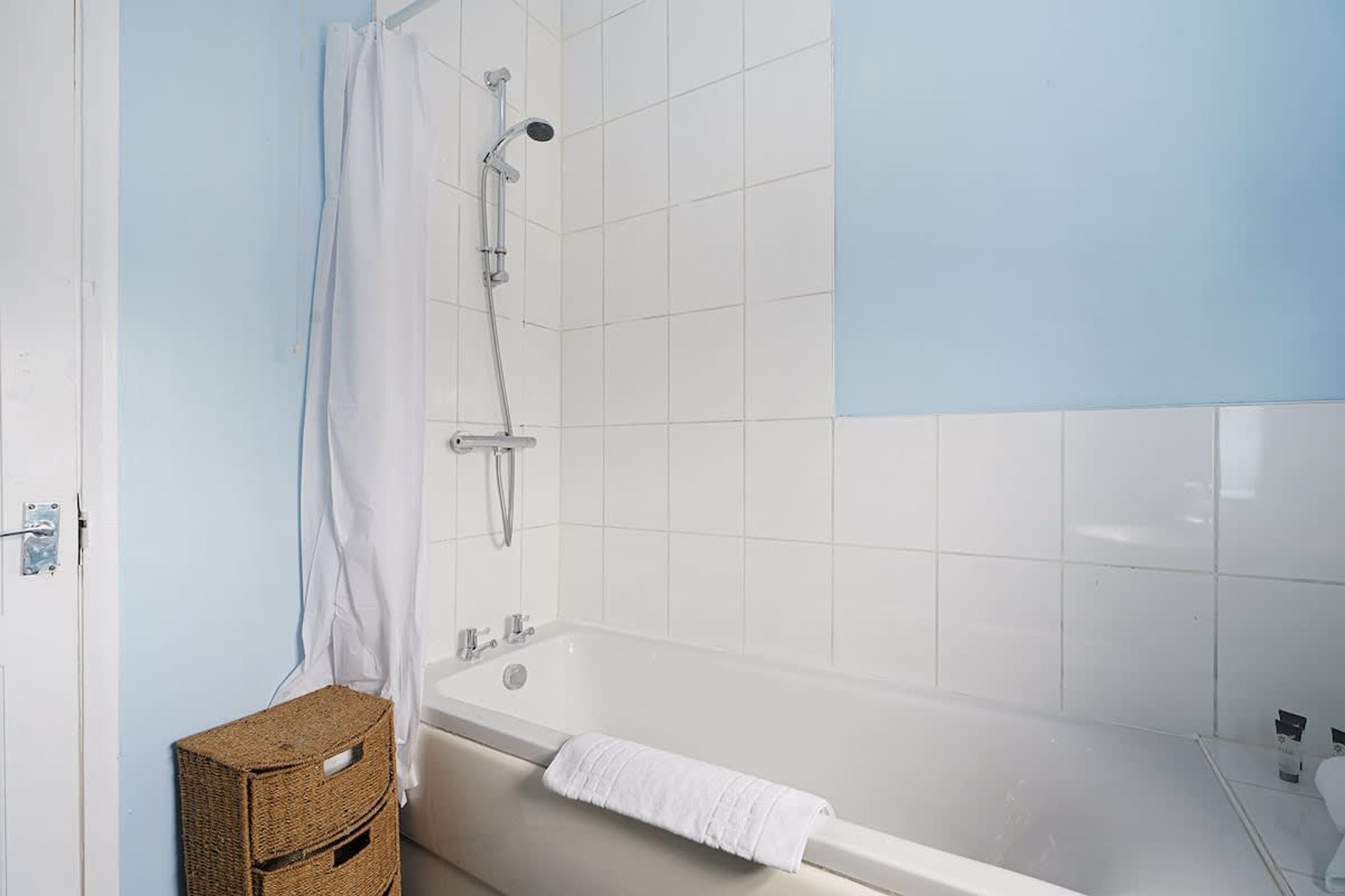 A bathroom with a bathtub, shower, and a towel rack.