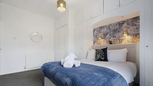 Ein Hotelzimmer mit einem Bett, einem runden Spiegel, einer Wand mit Marmoroptik und einer Deckenleuchte.