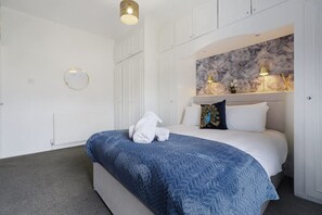 Ein Hotelzimmer mit einem Bett, einem runden Spiegel, einer Wand mit Marmoroptik und einer Deckenleuchte.