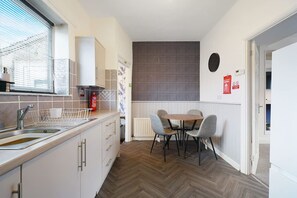 Een kleine keuken met een spoelbak, kastjes en een raam met jaloezieën.