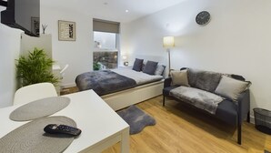 A modern bedroom with a bed, a sofa, a TV, a desk, and a window. - Perfect for Couples and Working Away in Manchester (Salford)