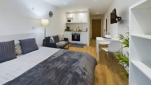 A modern hotel room with a bed, a desk, a kitchenette, and a seating area. - Perfect for Couples and Working Away in Manchester (Salford)