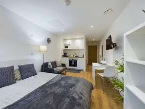 Ein modernes Hotelzimmer mit Bett, Schreibtisch, einer Küchenzeile und einer Sitzecke.