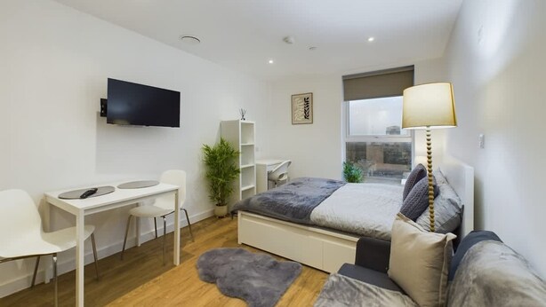 A modern bedroom with a bed, a desk, a chair, a TV, and a window. - Perfect for Couples and Working Away in Manchester (Salford)
