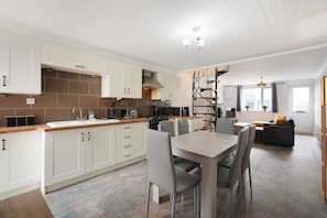 A modern kitchen with white cabinets, a wooden countertop, and a dining area with a table and chairs.