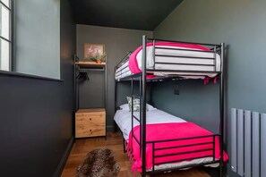 A bunk bed room with a wooden dresser, a leopard print rug, and a radiator. - Beautiful 2 Bed Near Barnard Castle Attractions (Barnard Castle)
