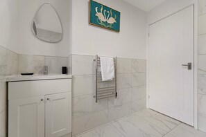 A bathroom with a vanity, a towel rack, a mirror, and a door. - Castle-side 2 Bed - Stroll to Historic Attractions (Barnard Castle)