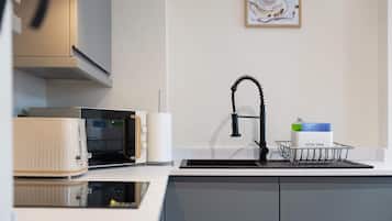 A modern kitchen with a microwave, toaster, sink, and a framed picture on the wall.
