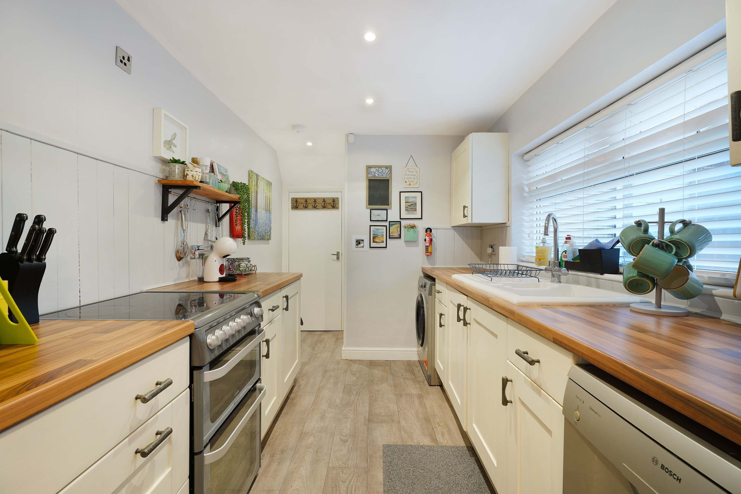 A modern kitchen with white cabinetry, a wooden countertop, and a built-in oven.